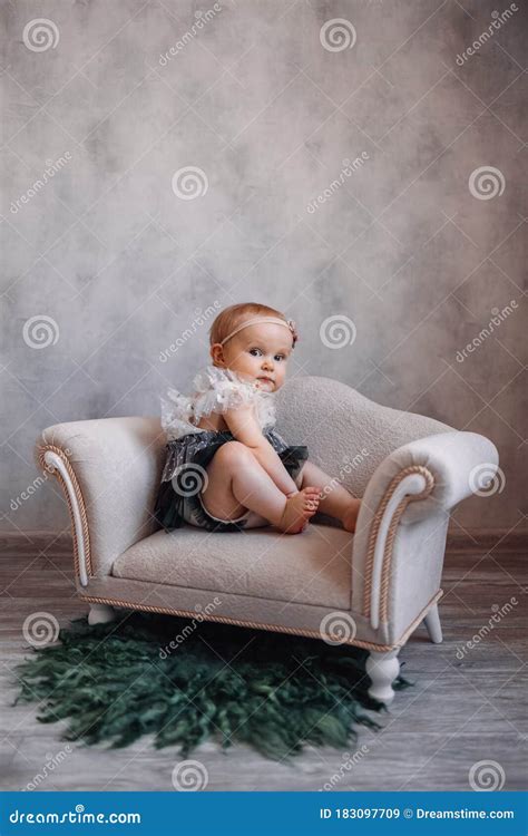 Cute Serious Newborn Baby Sitting On Sofa Infant Girl Sitting On