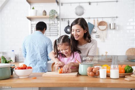 mother teaching daughter chopping carrot on cutting board foto de stock getty images