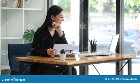 Cheerful Young Asian Female Entrepreneur Sitting In Bright Modern