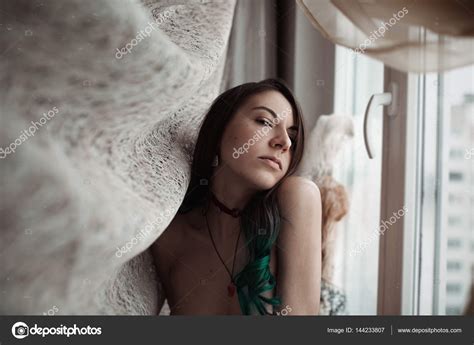 Retrato de una chica desnuda junto a la ventana fotografía de stock