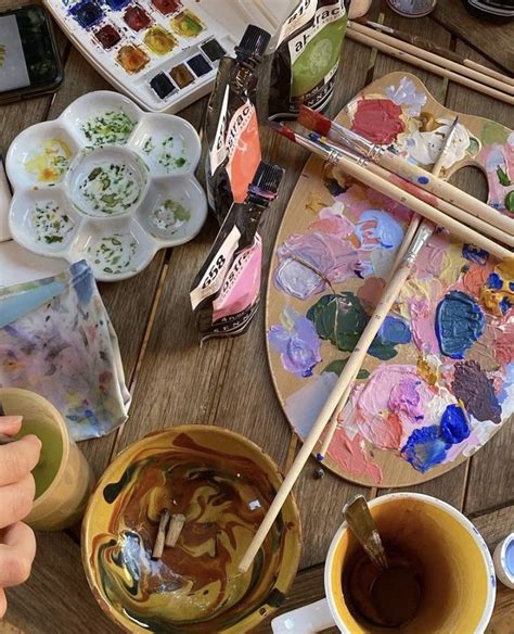 An Artists Table With Paints Brushes And Palettes