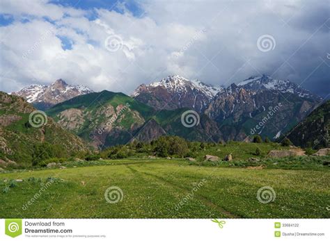 Mountains Covered With Snow A Green Meadow With A Stock Photo Image