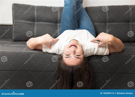 Young Beautiful Brunette Woman Lying On The Sofa Upside Down In Her Appartment Feeling Cozy At