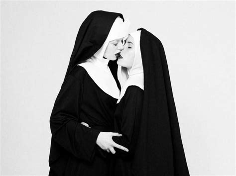two women dressed in nun costumes kissing each other s foreheads while standing side by side