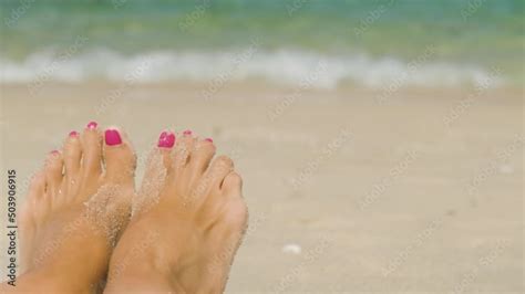 A Close Up POV Shot Of The Pedicured Feet Of A Babe Female Sunbathing On An Ocean Beach The