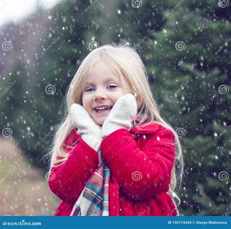 Portrait Of Smiling Little Girl Standing In Snowfall Stock Photo