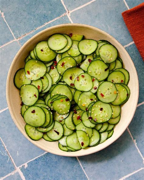 A Bowl Filled With Sliced Cucumbers On Top Of A Blue Tile Floor