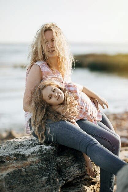 Premium Photo Happy Beautiful Mother And Her Daughter Having Fun On The Rocky Beach At Sunset