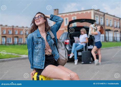 Three Girlfriends Go On A Road Trip Young Woman Posing With A Suitcase Two Girls Are Sitting