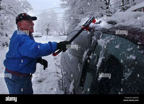 Man Scraping Off Snow And Ice From A Car Automobile After A Snow Storm