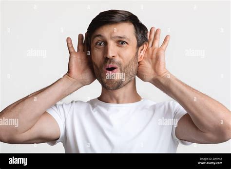 Curious Man Holding Hands Near Ears Listening News White Background