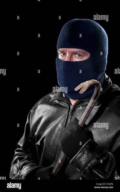 A Thief Wearing A Ski Mask To Hide His Identity Holds A Crowbar And
