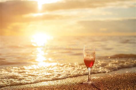 Romantic Beach Scene Glass Of Red Wine At Sunset Near Water Line Stock