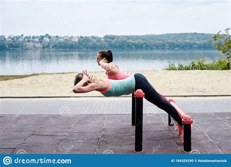Two Young Women Wearing Sports Outfit Doing Sit Ups On Horizontal