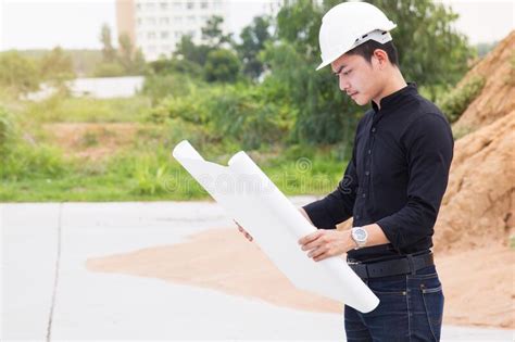 Young Engineer Surveying Land To Construction House Using Blueprint To
