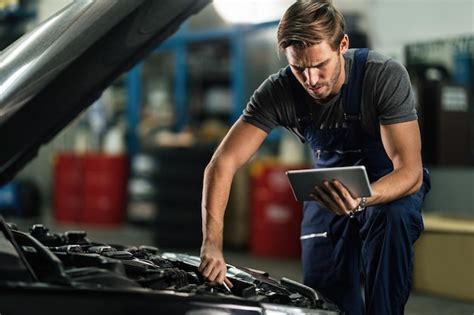 Free Photo Young Auto Repairman Working On Car Engine While Using