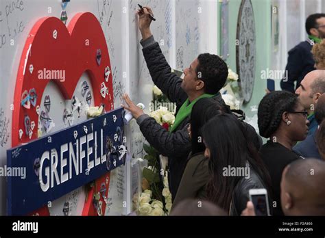 People sign a remembrance wall near the Grenfell Tower anniversary