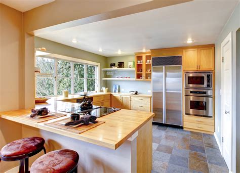 Una barra en metal se puede empotrar fácilmente a uno de los muros de la cocina, creando una barra para desayunar. ¿Qué prefieres: cocinas con barra americana o isla central?