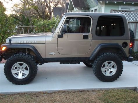 A Tan Jeep Parked In Front Of A House