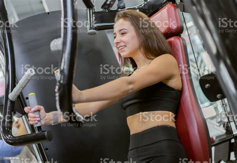 Young Fit Woman Trains Pectoral Muscles In Exercise Machine At The Gym