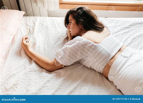 Portrait Of Young Sad Woman Lying On The Bed Looking Smartphone Feels Unhappy Waiting For