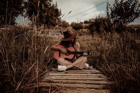 Woman Holding Guitar Sitting On Dock · Free Stock Photo