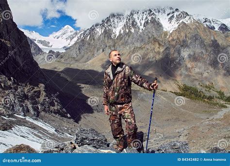 Survival In The Wild A Man In Camouflage Resting Among The Mountains
