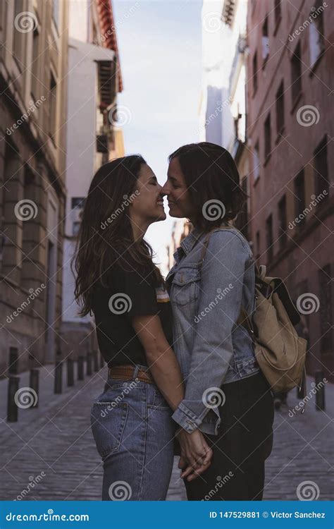 aantrekkelijk jong vrouwen lesbisch paar die en in een straat van madrid kussen glimlachen stock