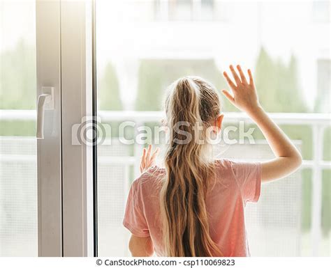 Sad Little Girl Looking Through Window At Home Lonely Little Girl