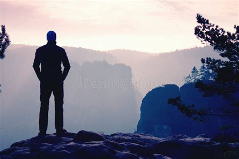 Self Confident Hiker In Akkimbo Pose On The Peak Of Rock Stock Photo