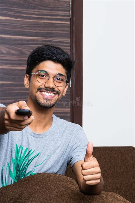Young Indian Boy Pointing The Television Remote And Smiling Stock Photo