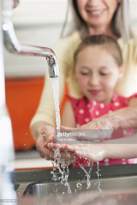 Grandmother Helping Granddaughter To Wash Her Hands High Res Stock