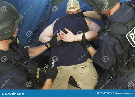 Policeman Putting Handcuffs On Drug Dealer In Abandoned House Catching Criminal Stock Image