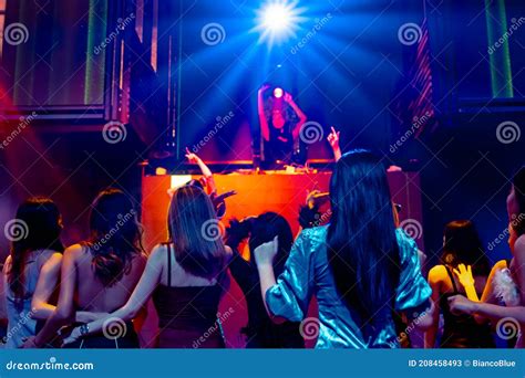 group of people dance in disco night club to the beat of music from dj on stage stock image