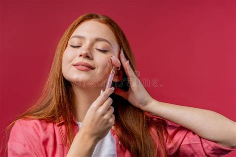 Mulher Gengibre Fazendo Massagem Facial Com Rolo De Pedra Quartzo Rosa Em Fundo Rosa Rituais