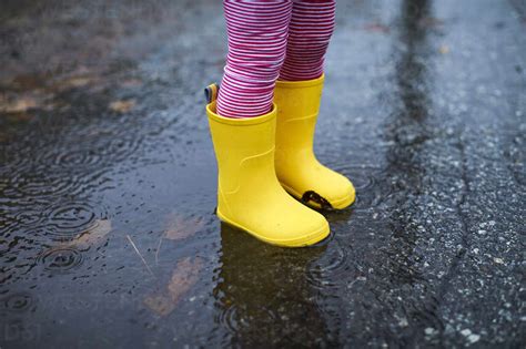A Close Of Up A Childs Rain Boots In A Puddle Lizenzfreies Stockfoto