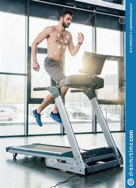 Handsome Muscular Sportsman With Electrodes Running On Treadmill During