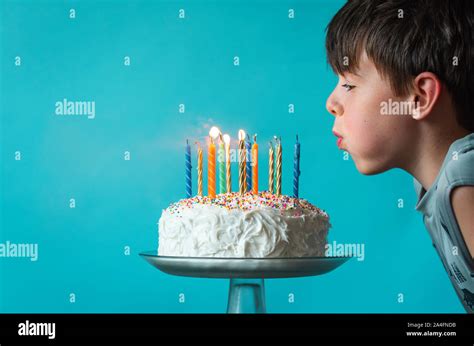 Boy Blowing Out Candles On A Birthday Cake Against Blue Background