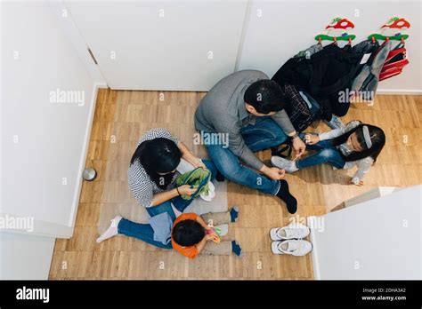 High Angle View Of Father Tying Daughter S Shoelace While Mother Sitting With Son On Floor At