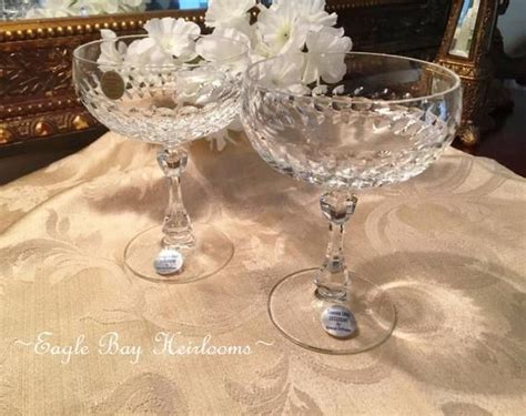 Two Clear Goblets With White Flowers In Them On A Table Next To A Mirror