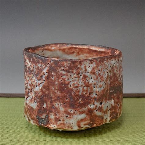 A Brown And White Bowl Sitting On Top Of A Green Tablecloth Next To A