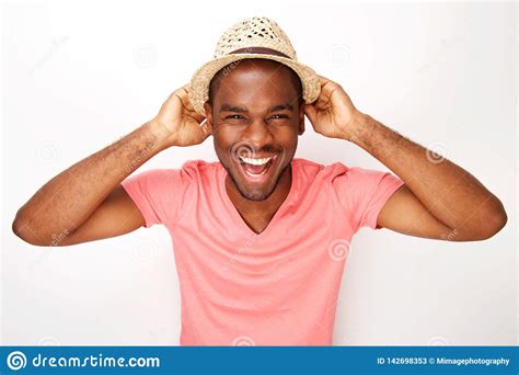 Cheerful Young Black Man Laughing With Hat Against White Wall Stock