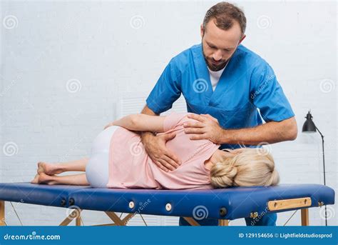 Chiropractor Massaging A Young Woman Lying On A Massage Table Stretching And Flexing Her Feet