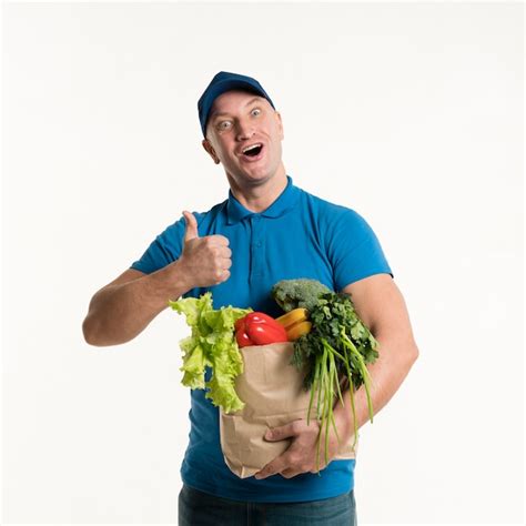 Free Photo Delivery Man Giving Thumbs Up And Holding Grocery Bag