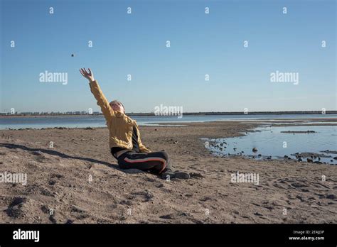 Boy Sitting Alone On Sandy Beach And Throwing Stones Stock Photo Alamy