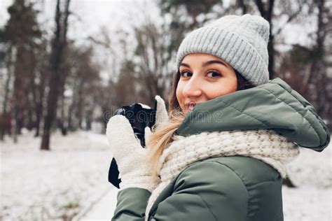 Woman Photographer Takes Pictures Of Snowy Winter Park Using Camera Wearing Warm Clothes
