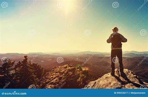 Man Standing At The Edge Of A Cliff Overlooking The Mountains Stock