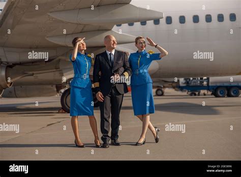 Full Length Shot Of Happy Pilot Standing Together With Two Stewardesses