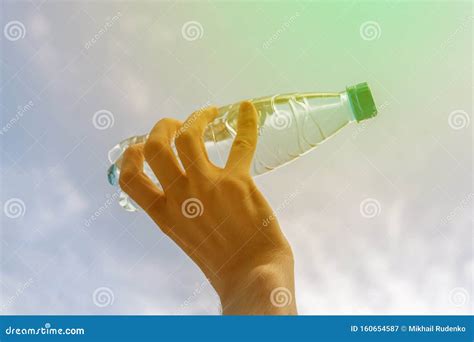 Hand Holding A Plastic Bottle With Pure Water Against Sky Stock Image