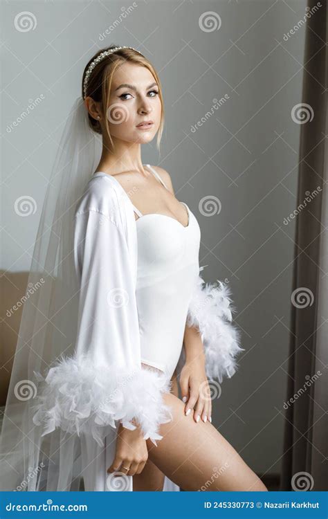Gorgeous Beautiful Bride In Silk Robe Posing Near Window In Soft Light